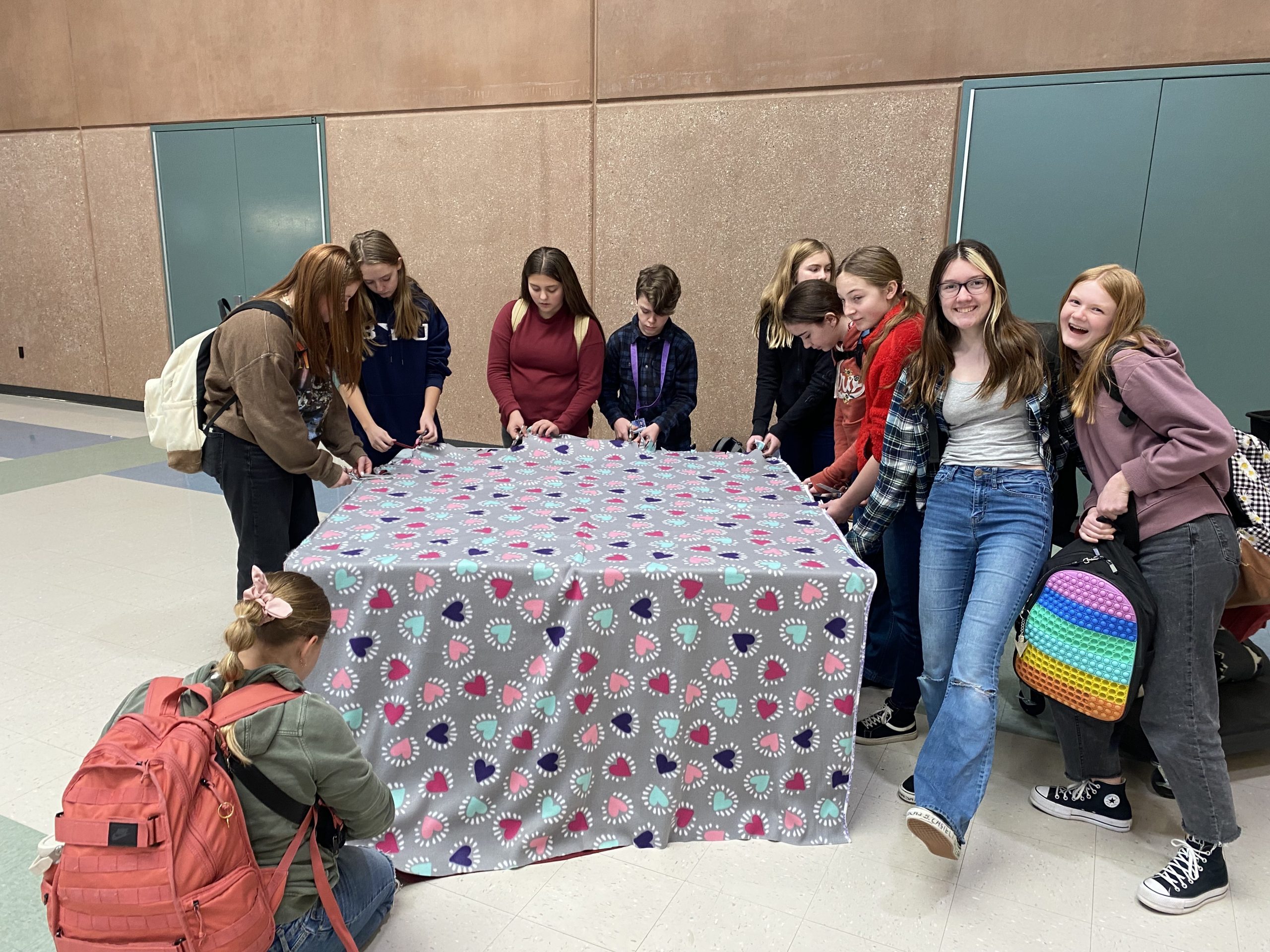 Ten students work on tying a blanket for the police department.