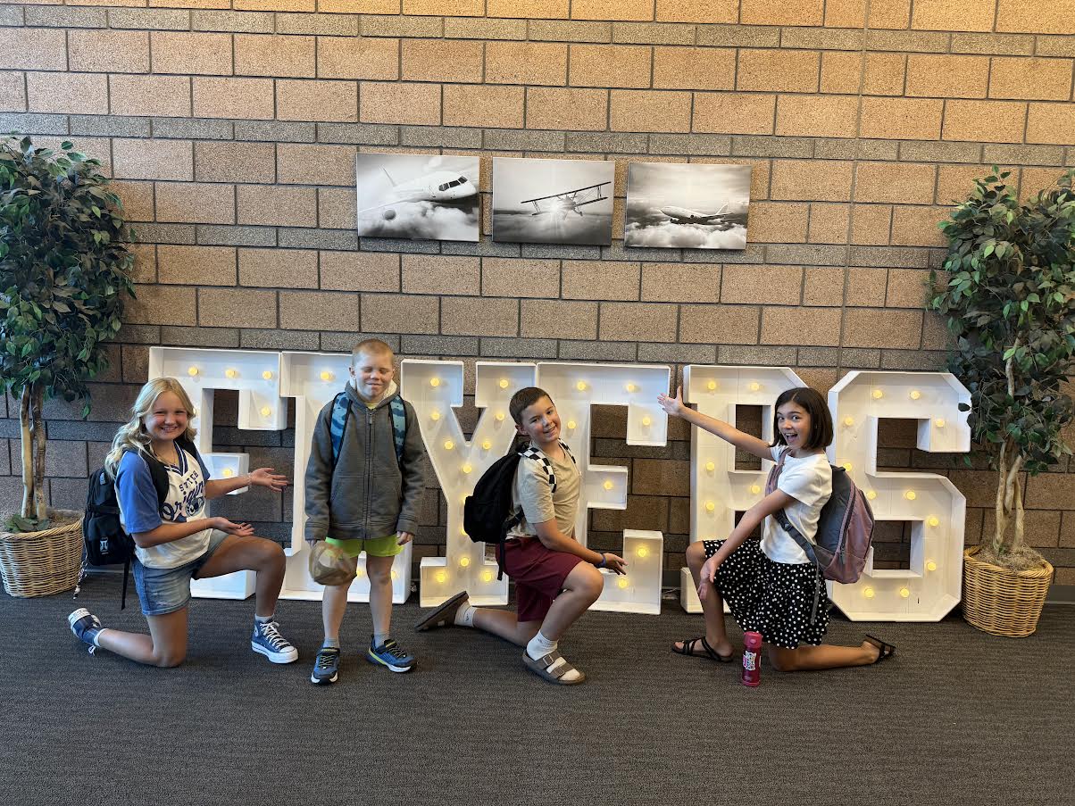 Two boys and two girls show off the large light up FLYER marquee letters in the foyer.