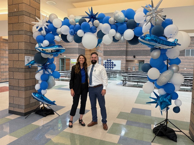 Principal Roden and AP Tuttle standing under the Flyer balloon arch ready to welcome students on the first day of school.