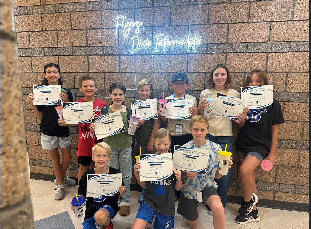 10 students stand in front of the "Flyers Dixie Intermediate" light with their decorated tumblers and student of the month certificates. Congrats to our September students of the month.