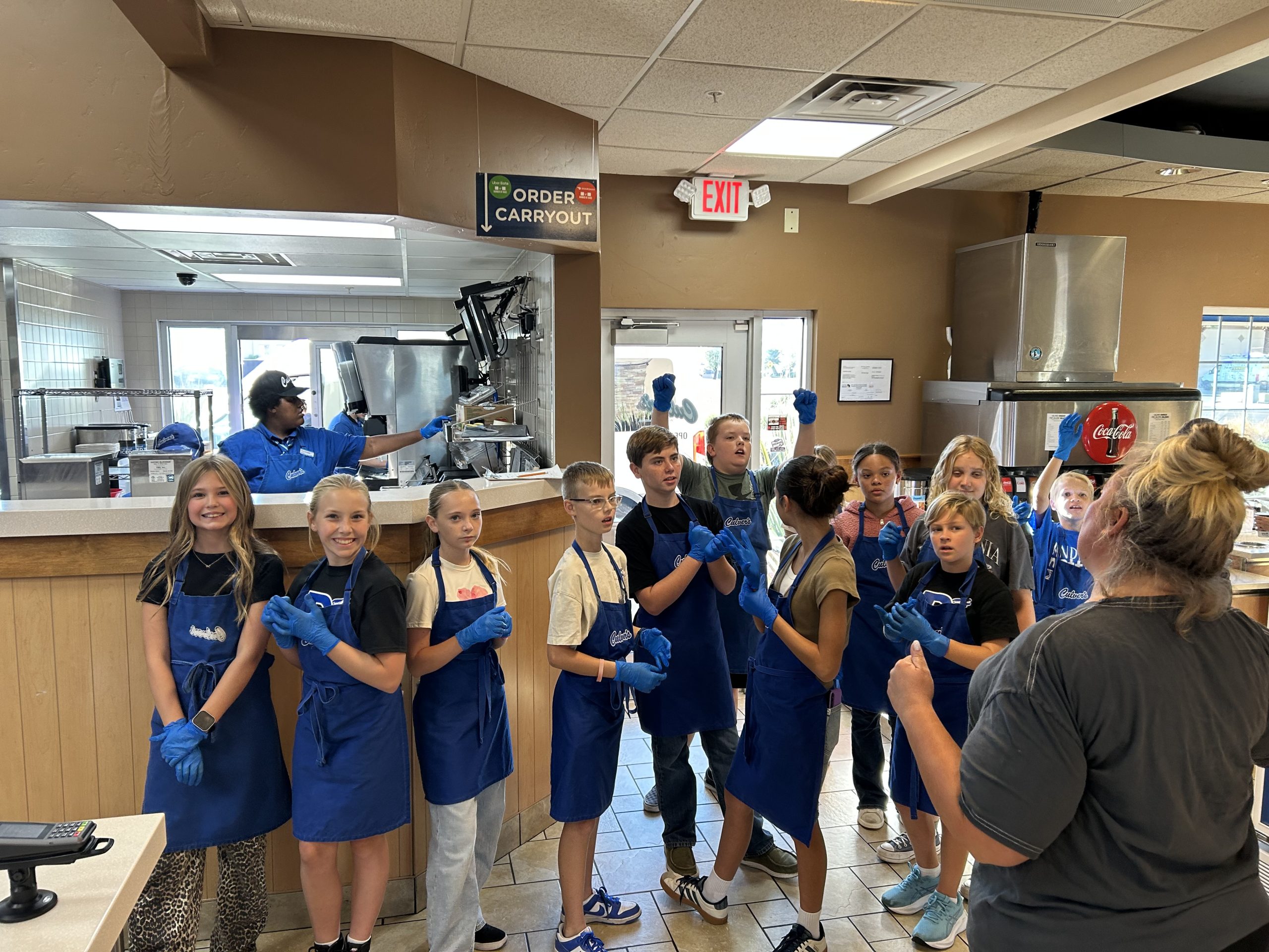 11 DIS Students ready in their Culver's aprons and blue plastic gloves for Culver's Night.