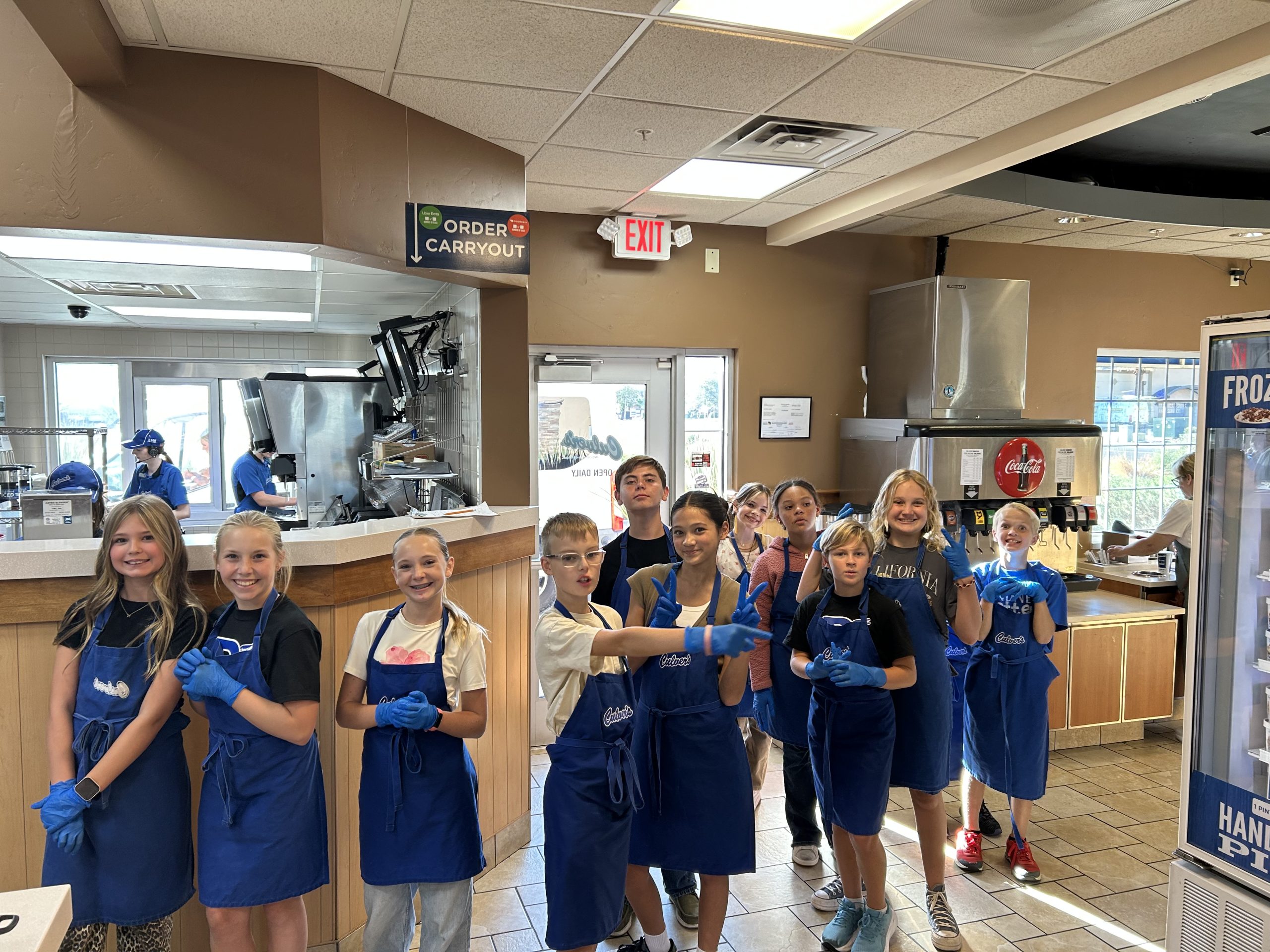 11 DIS Students ready in their Culver's aprons and blue plastic gloves for Culver's Night.